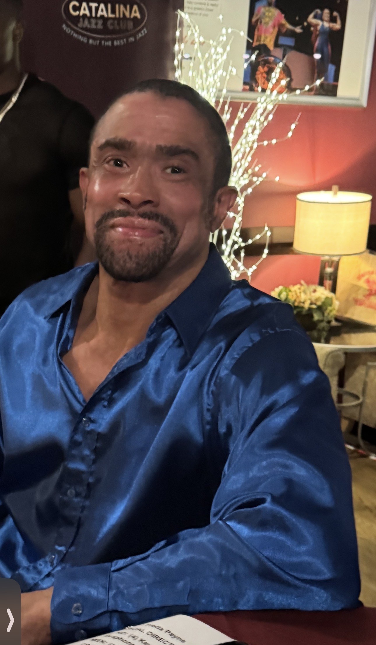 Gregory Abbott Jr. in a blue satin shirt at Catalina Jazz Club, the running sheet on the table in front of him